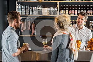 Bartender Talking With Customers At Bar Counter