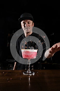 Bartender is throwing roses over pink Clover club alcoholic cocktail at the bar. Bartender mixes egg white, lemon, dry