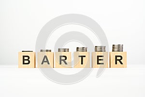 barter - text written on wooden block with stacked coins on white background, growing trend