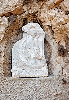 Bas-relief in the Castle of Santa Barbara ruined chapel. A warrior with sword fighting dragon. Alicante, Spain.