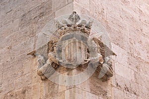 Bas-relief of old coat of arms shield on the entrance with catalan flag, angels and crown