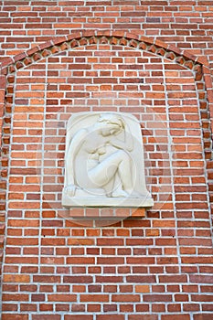 Bas-relief The squating girl (Genius) on a red brick wall. Kaliningrad