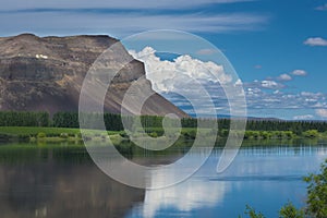 Basalt mountain cliffs overlooking columbia river grant county mattawa with crystal blue skies and reflection in the water