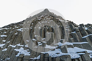 Basaltic or HÃ¡lsanef snow columns from below Reynisfjara Black Beach or VÃ­k Black Beach with clear sky about to snow