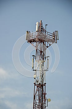 Base transceiver station (BTS) with antenna isolated on blue sky background. Telecommunications radio tower cells