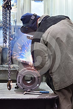 The base for the valve is mounted on the iron table at the factory and the worker welds with a welding machine. Sparks