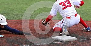 Basebal player head first sliding into third wearing sliding gloves