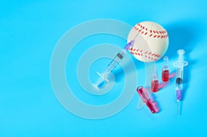 Baseball ball near syringe and ampoule on blue background. Concept of doping in professional sport