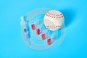 Baseball ball near syringe and ampoule on blue background. Concept of doping in professional sport