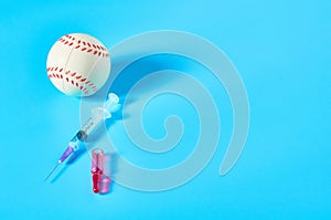 Baseball ball near syringe and ampoule on blue background. Concept of doping in professional sport