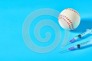 Baseball ball near syringe on blue background. Concept of doping in professional sport