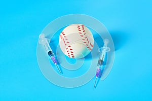 Baseball ball near syringe on blue background. Concept of doping in professional sport