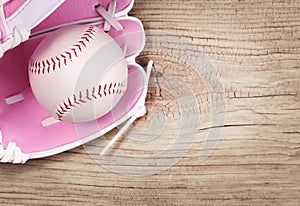 Baseball. Ball in Pink Female Glove over wood background
