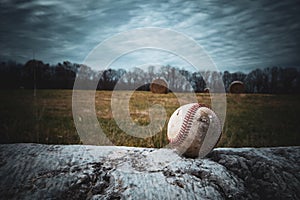 Baseball on a barrier near a field with grass hays