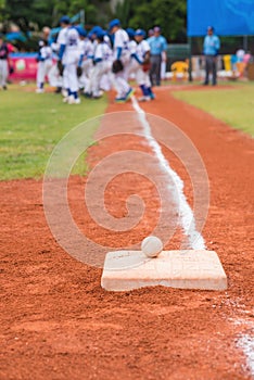 Baseball and base on baseball field with players and judges