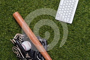 Baseball bat, ball, glove and computer keyboard isolated on a field of grass. Flat lay, top view. Sport home and workout online co