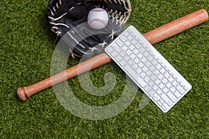 Baseball bat, ball, glove and computer keyboard isolated on a field of grass. Flat lay, top view. Sport home and workout online co