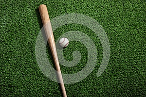 Baseball bat and ball on green turf background