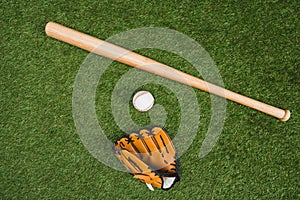 Baseball bat with glove and ball on green grass