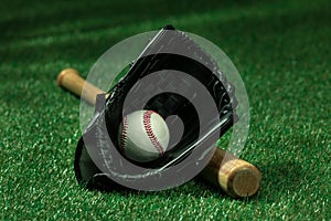 Baseball bat, glove and ball lying on green field