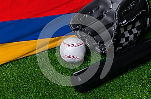 Baseball bat, glove and ball near Armenia flag on green grass background