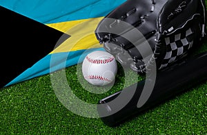 Baseball bat, glove and ball near Bahamas flag on green grass background