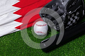 Baseball bat, glove and ball near Bahrain flag on green grass background