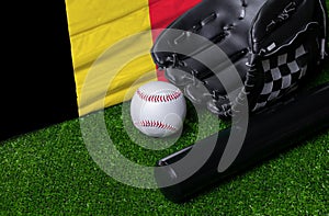 Baseball bat, glove and ball near Belgium flag on green grass background