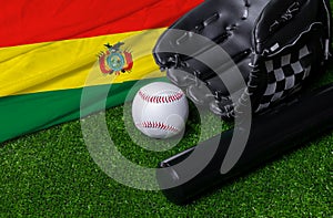 Baseball bat, glove and ball near Bolivia flag on green grass background