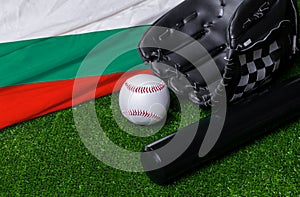 Baseball bat, glove and ball near Bulgaria flag on green grass background