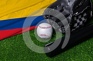 Baseball bat, glove and ball near Colombia flag on green grass background