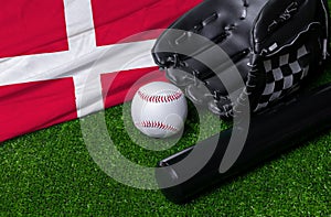 Baseball bat, glove and ball near Denmark flag on green grass background