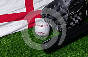 Baseball bat, glove and ball near England flag on green grass background