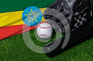 Baseball bat, glove and ball near Ethiopia flag on green grass background