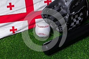 Baseball bat, glove and ball near Georgia flag on green grass background