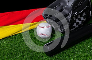 Baseball bat, glove and ball near Germany flag on green grass background