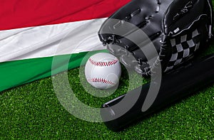 Baseball bat, glove and ball near Hungary flag on green grass background