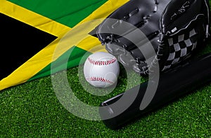 Baseball bat, glove and ball near Jamaica flag on green grass background
