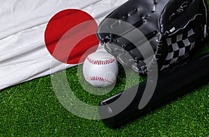 Baseball bat, glove and ball near Japan flag on green grass background