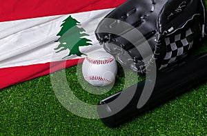 Baseball bat, glove and ball near Lebanon flag on green grass background