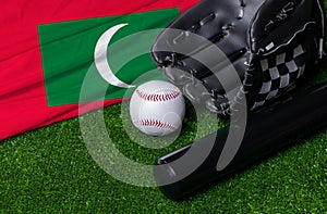 Baseball bat, glove and ball near Maldives flag on green grass background