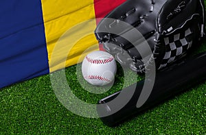Baseball bat, glove and ball near Romania flag on green grass background