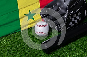 Baseball bat, glove and ball near Senegal flag on green grass background