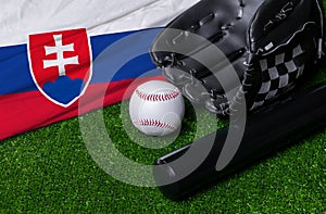 Baseball bat, glove and ball near Slovakia flag on green grass background