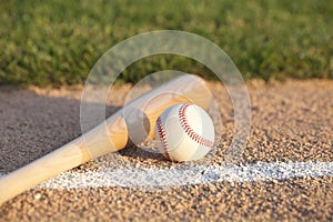 Baseball and bat laying on basepath with grass infield photo