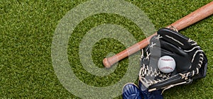 Baseball bat, shoes, glove and ball on green grass field. Sport theme background with copy space for text and advertisment photo