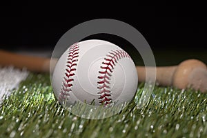 Baseball close up low angle with bat on grass field and black background