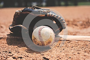 Baseball on field with glove close up in dirt.