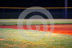 Baseball Floating inches above an empty baseball field at night time