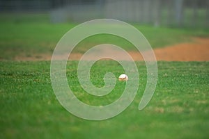 Baseball game, baseball ball siting on the grass on the diamond near the pitcher\'s mound during the ball game